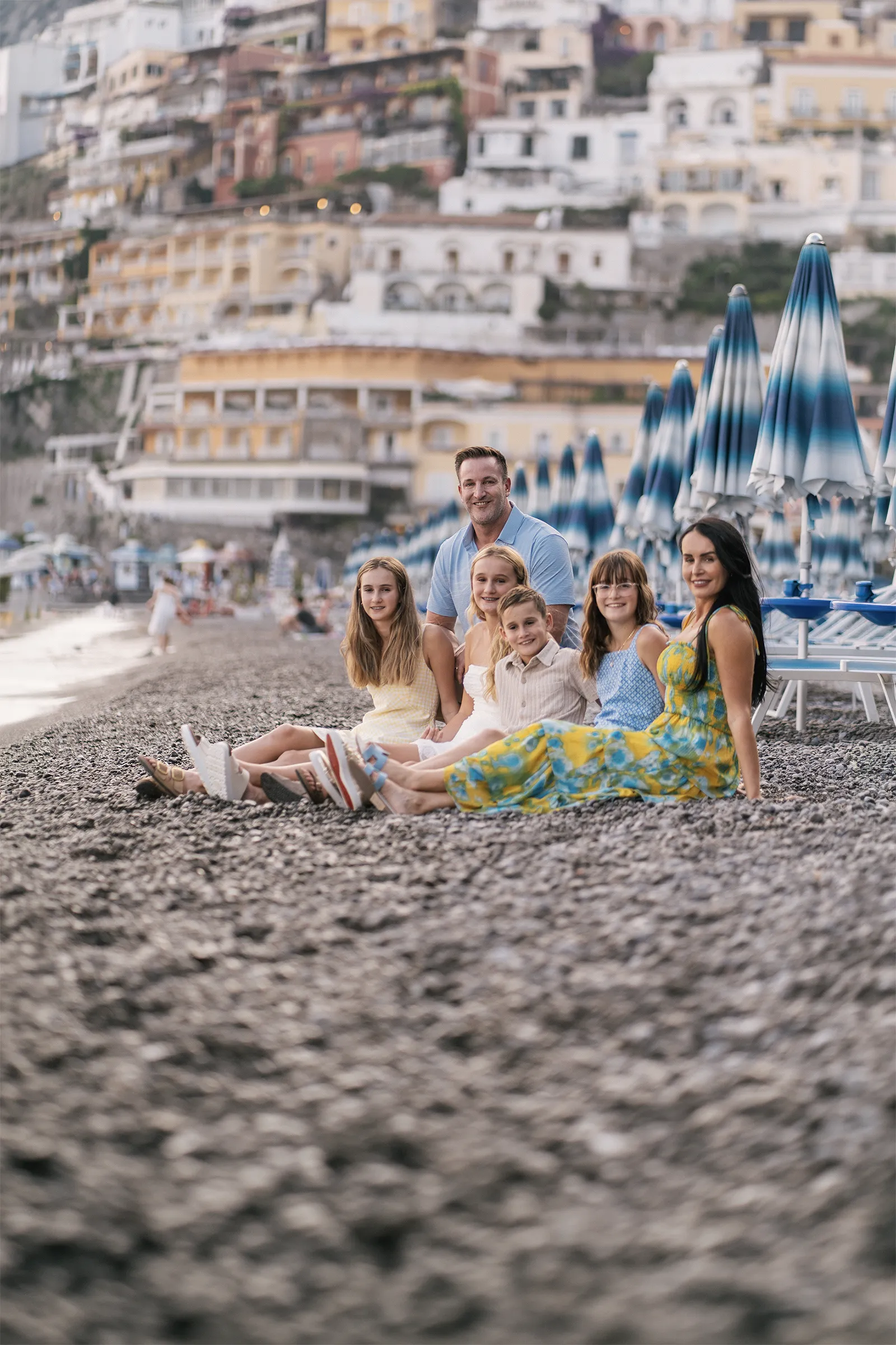 Family photoshoot in Positano on the beach with colorful Amalfi Coast houses in background