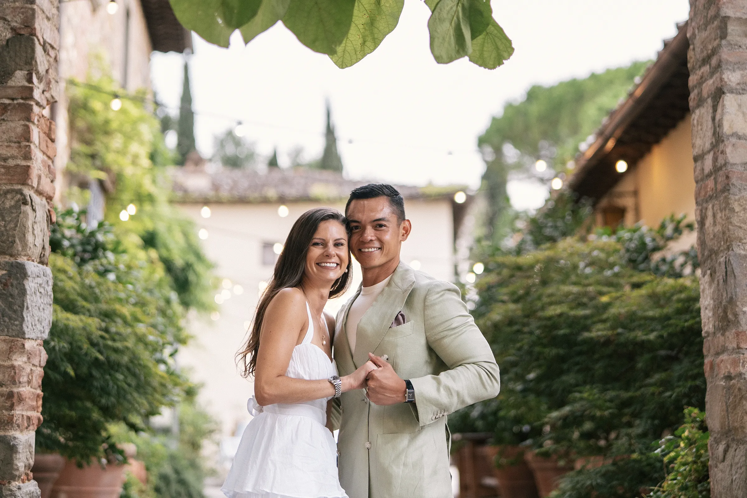 Romantic couple photoshoot in Tuscany courtyard with stone arch and greenery