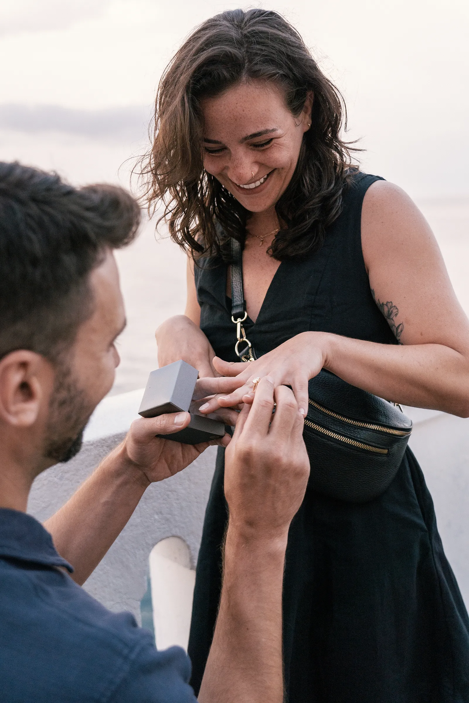 Close-up of engagement ring being placed on woman's finger during sunset proposal