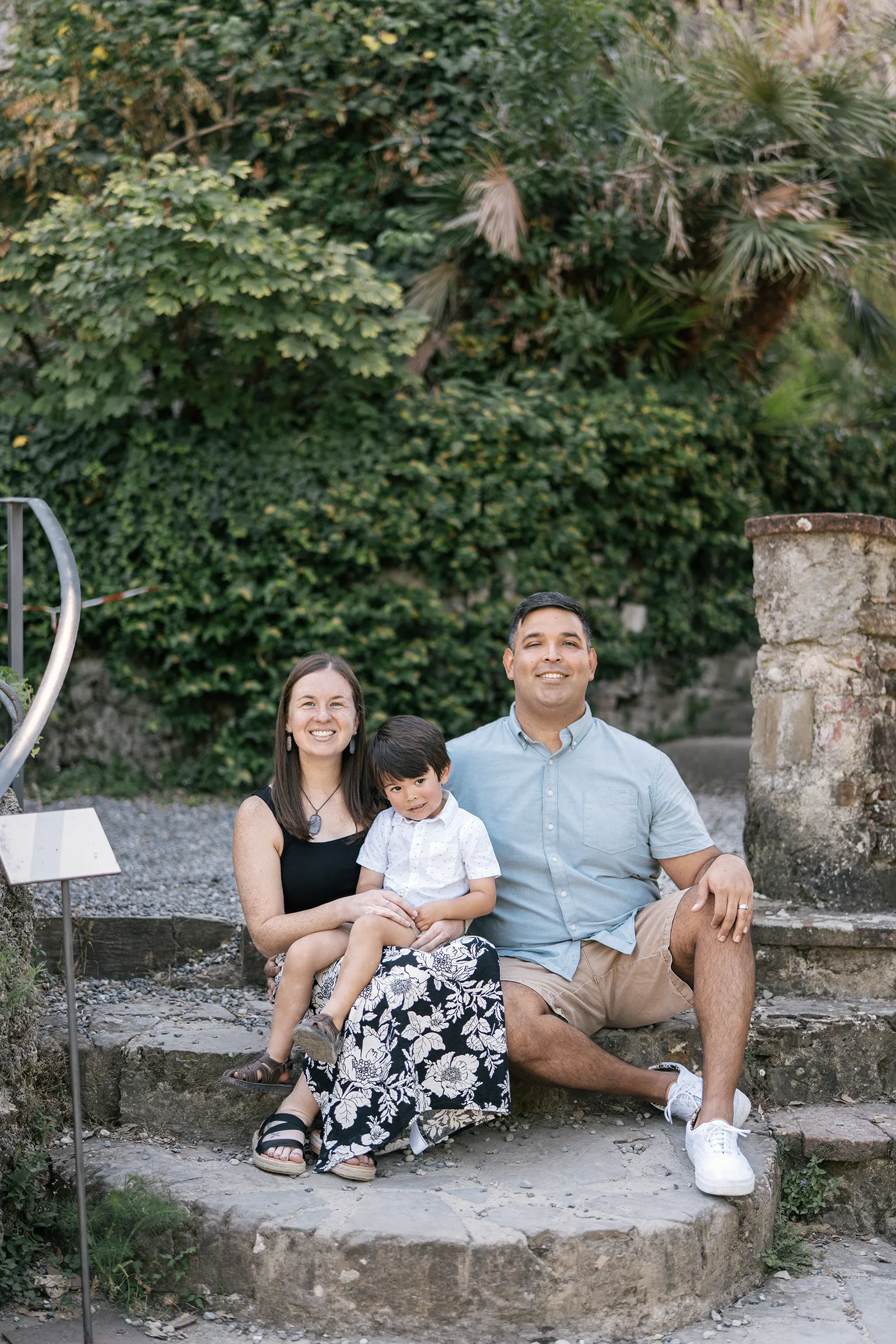 Family portrait session in Tuscany with parents and child sitting on stone steps
